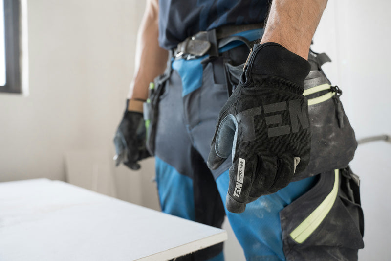Handwerker hüfthoch in blau-schwarzer Arbeitskleidung