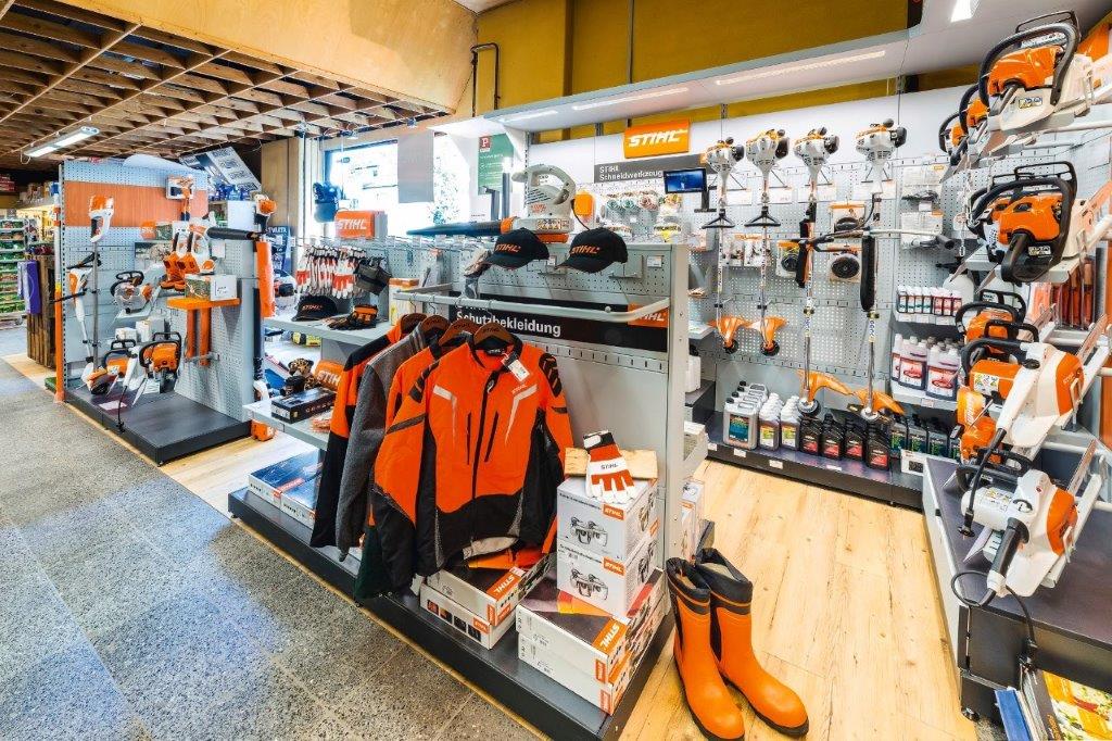 Regale mit Ware von der Marke STIHL in Orange, wie Jacken, Geräte, Schuhe und Zubehör