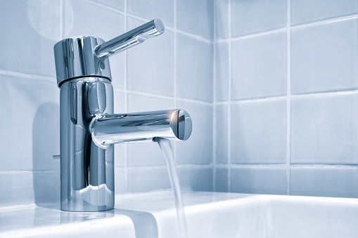 Ein laufender Wasserhahn in Silber in einem Badezimmer